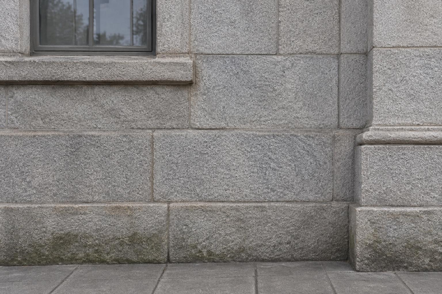 Granite building wall with the graffiti removed and the natural stone visible.