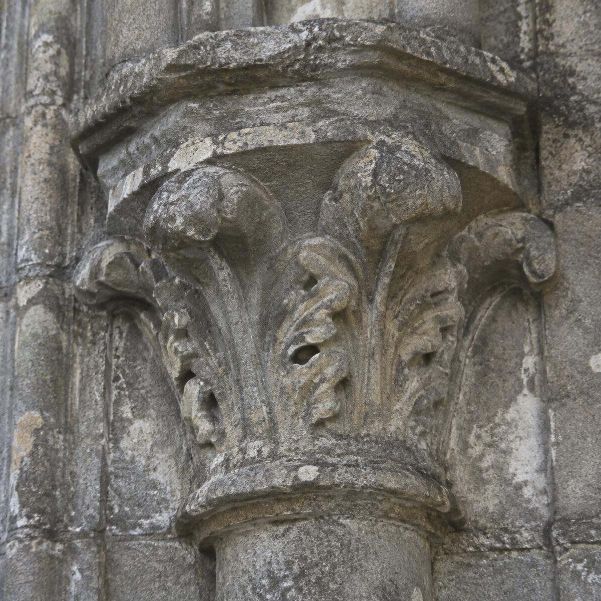 Close-up of a weathered carved stone capital on a historic building